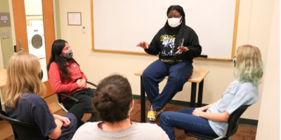 5 people sitting in a circle talking